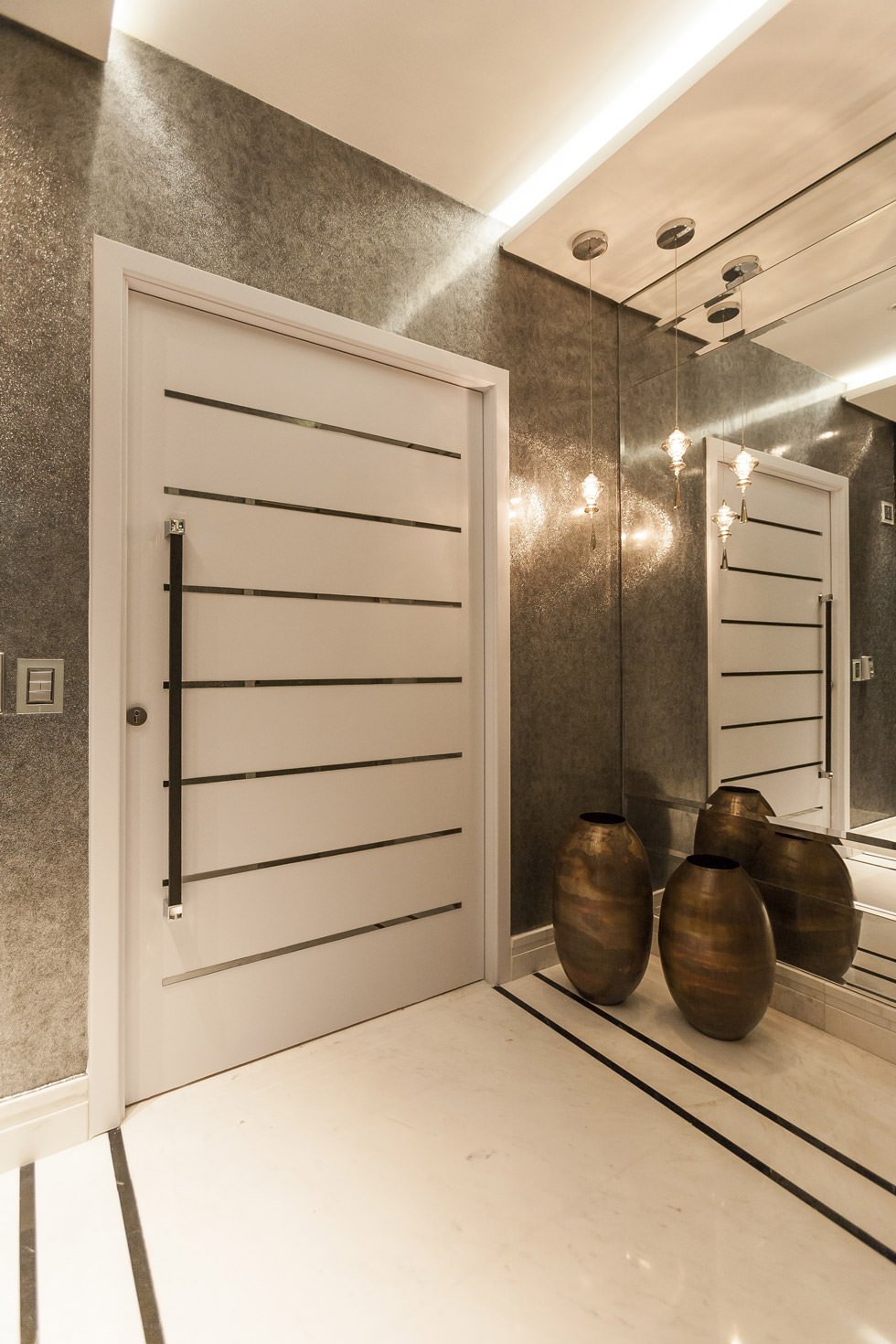 Immagine ingresso casa con porta blindata stile minimal moderno, abbinamento laminato bianco opaco e acciaio inox