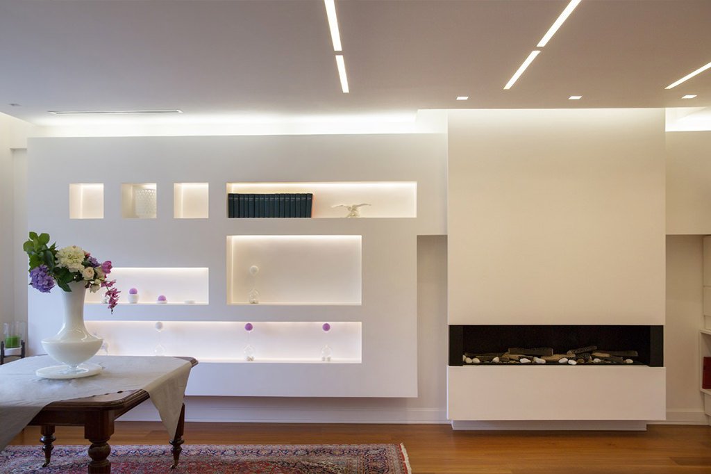 Dettaglio soggiorno moderno con camino e libreria in cartongesso con illuminazione a led - altre sorgenti di luce presenti nella parte alta della struttura e nel controsoffitto - articolo costo orario elettricista
