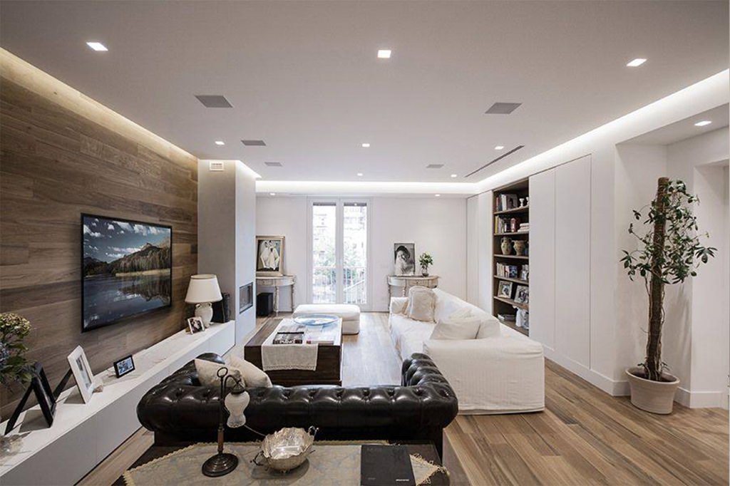 Particolare soggiorno moderno con parete rivestita in legno, stesso materiale del pavimento - illuminazione perimetrale a led sul soffitto e faretti da incasso - guida costo elettricista, manodopera e prezzo orario