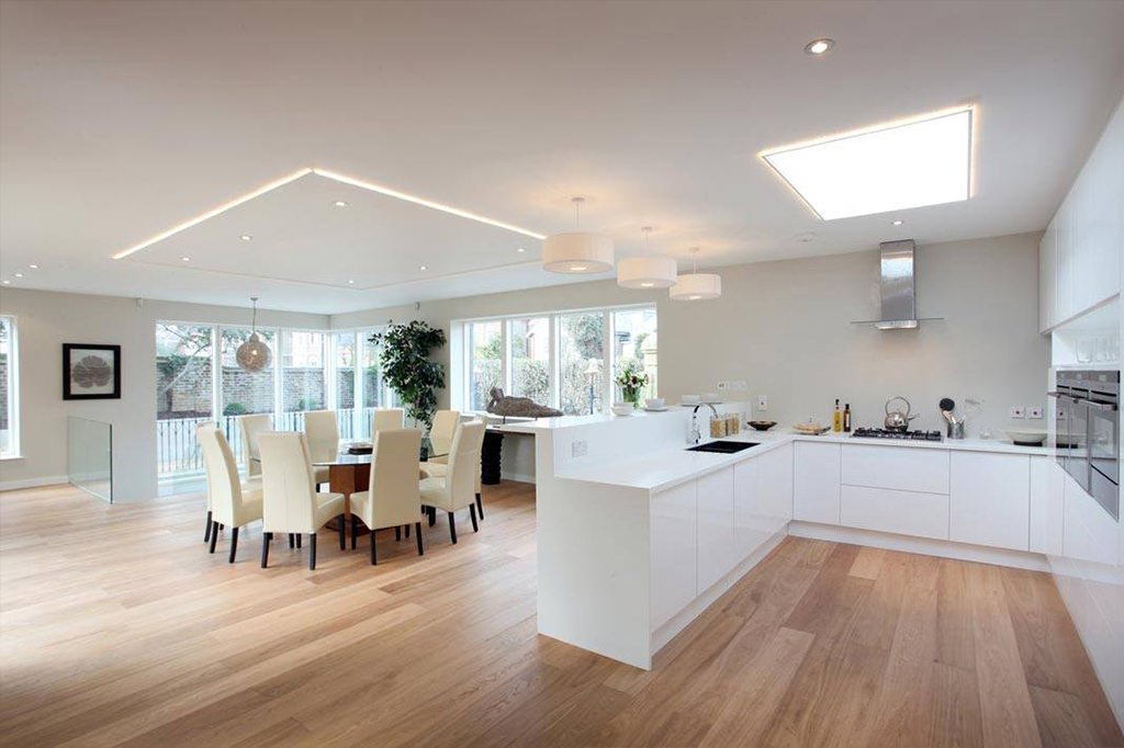 Luminoso open space con cucina con isola e sala da pranzo - mobili in lucidato bianco per aumentare la luce, soffitto con illuminazione a led, lampadari e faretti da incasso - guida completa sul prezzo elettricista - manodopera e preventivo elettricisti