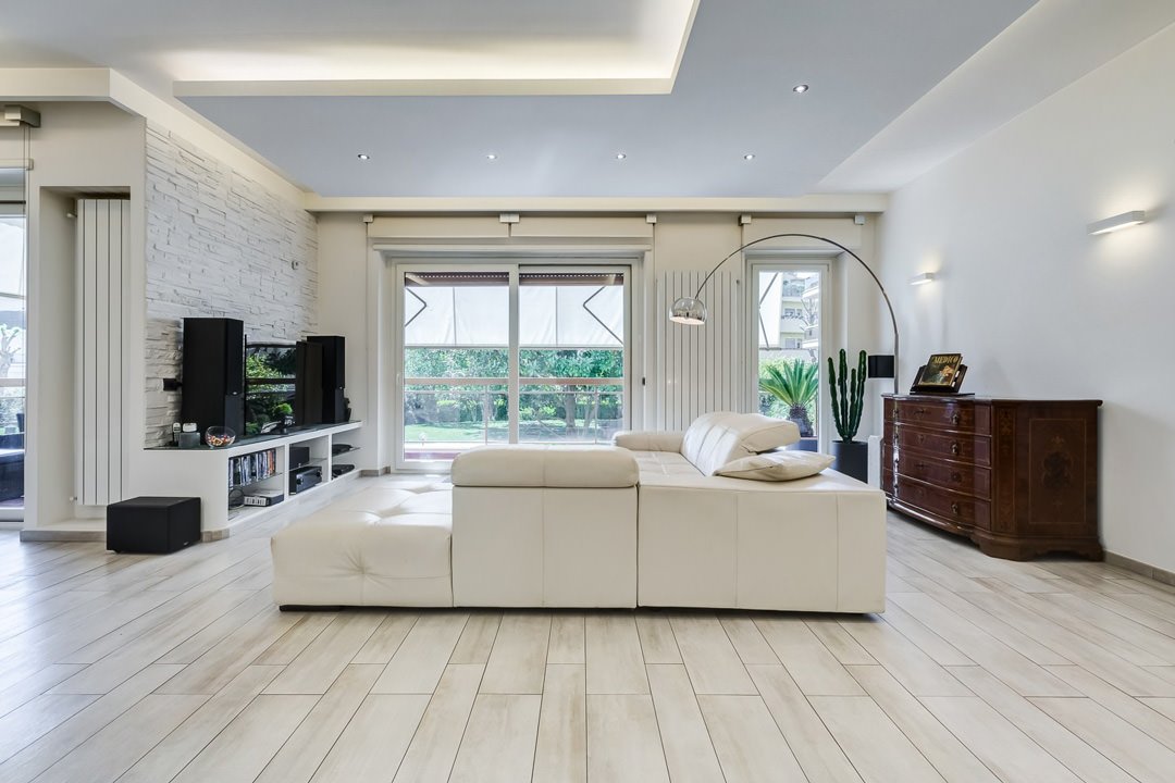Interessante idea di soggiorno contemporaneo con elementi moderni e vintage - divano bianco in pelle, mobili in legno, parete rivestita in pietra e pavimenti in legno