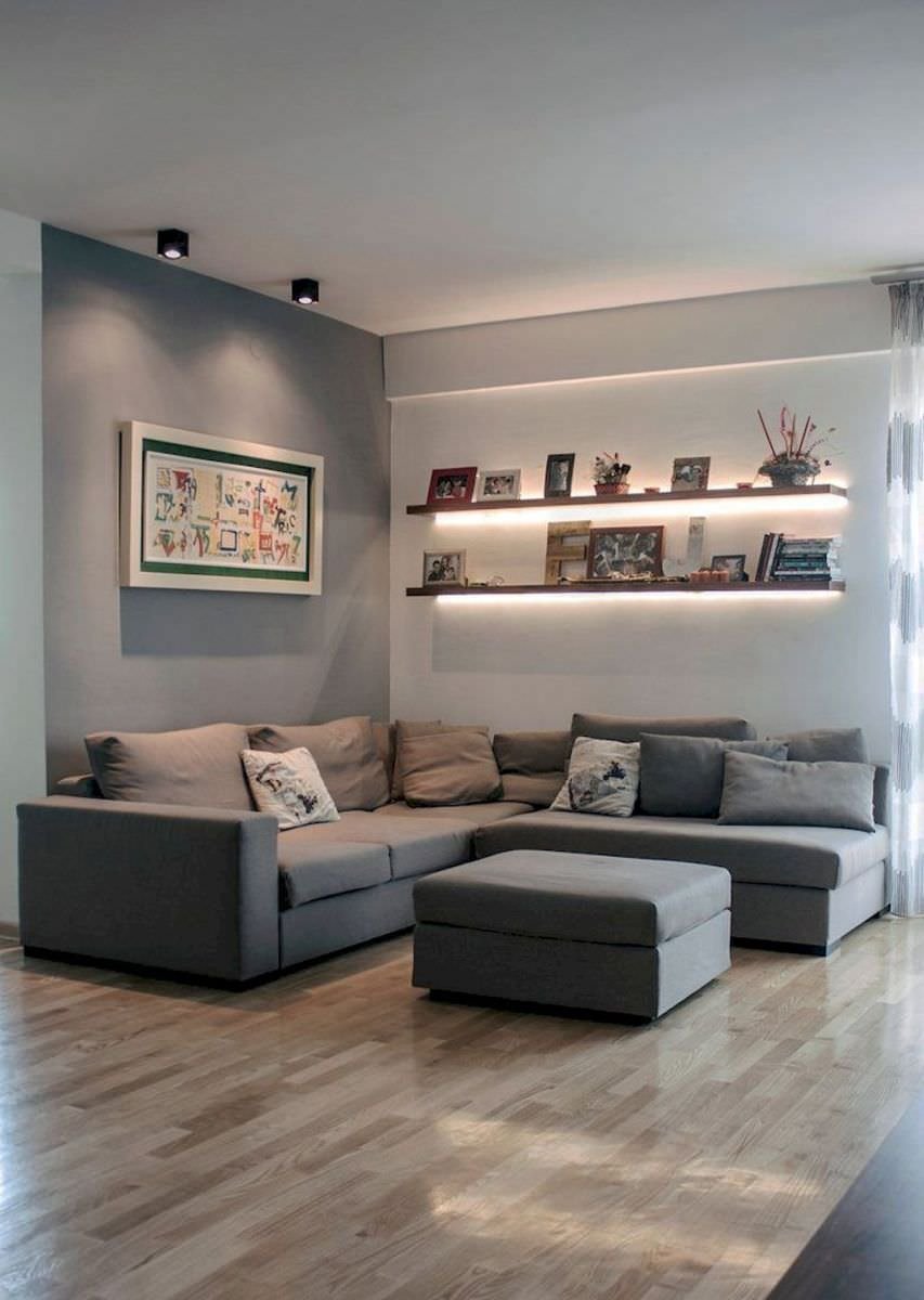 Living scandinavo moderno, sobrio ed elegante, in toni di grigio, con mensole illuminati da strisce led che donano dinamicità allo spazio. Divani in stoffa, parquet in frassino lucidato.