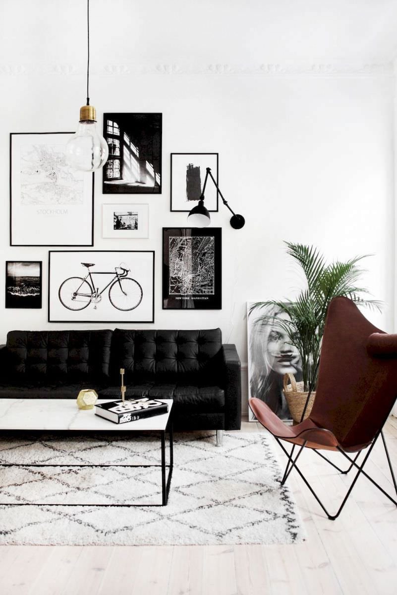 Living scandinavo moderno e dinamico, in contrasti di bianco e nero. Alcuni tocchi di colore donati dal pavimento in legno, la poltrona marrone e un cesto di piante.