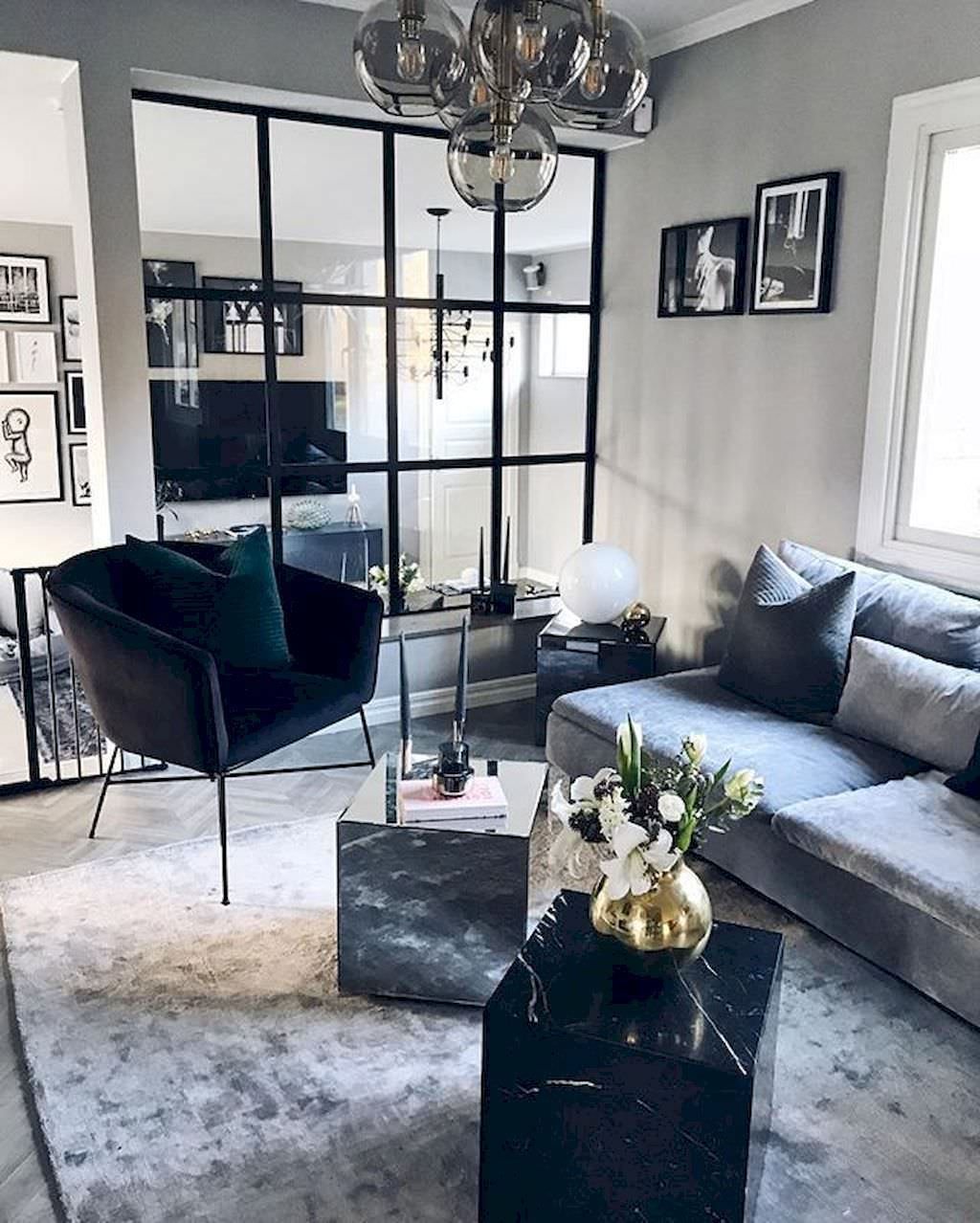 Salotto scandinavo raffinato ed elegante, con vari giochi di stile e di grande personalità. Pareti grigie e vari contrasti netti di bianco e nero. Molto interessante la parete vetrata che dona luminosità allo spazio.