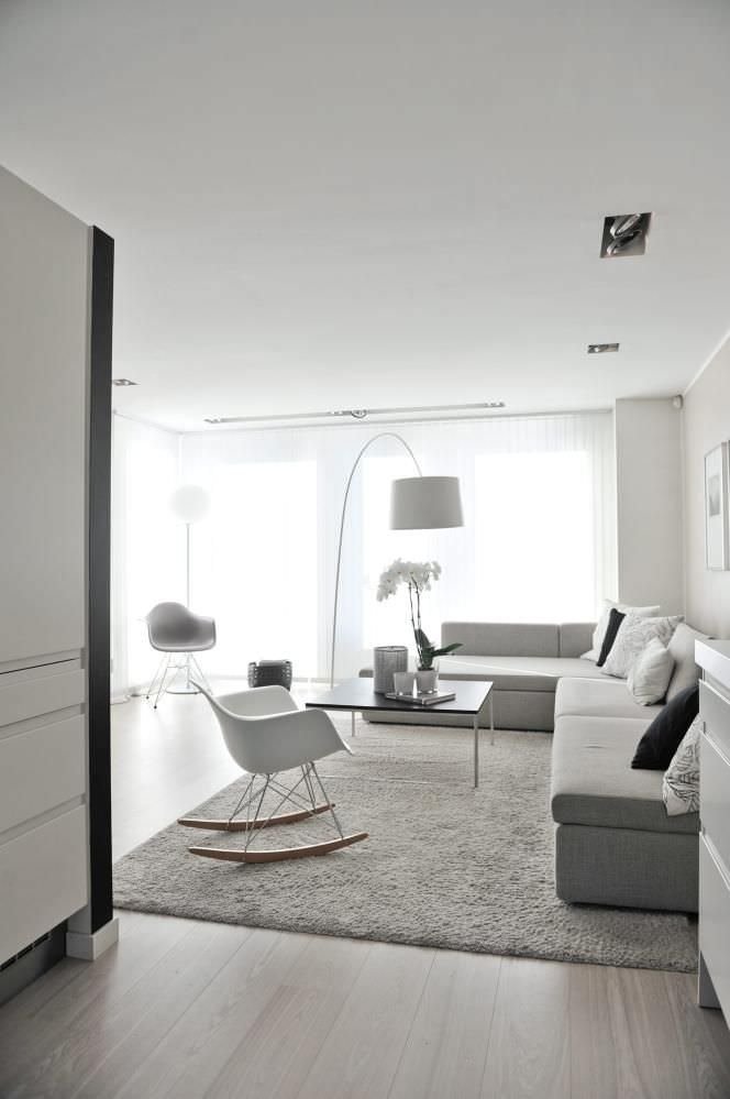 Bellissimo soggiorno scandinavo moderno, luminoso ed accogliente, con arredamento, tappeto e pareti colore grigio tortora. Lampada da terra ad arco e grandi finestre che assicurano una perfetto illuminazione della stanza.