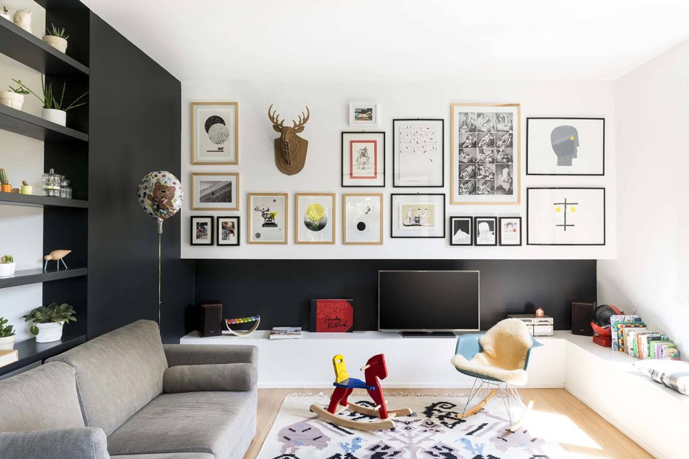 Salotto scandinavo moderno in contrasti di bianco e nero arricchito con alcuni tocchi di colore tra quadri, libri, decorazioni e giocatoli.