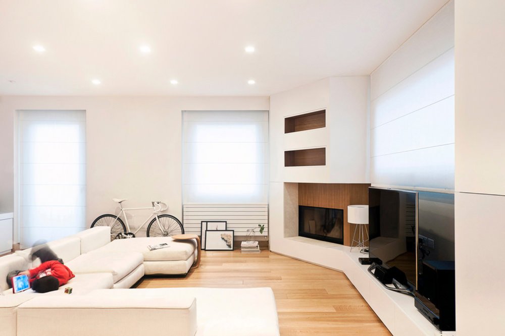 Parquet cerato e complementi d’arredo in total white donano eleganza e modernità a questo salotto. Parete attrezzata ad angolo obliquo con tv, camino e libreria.