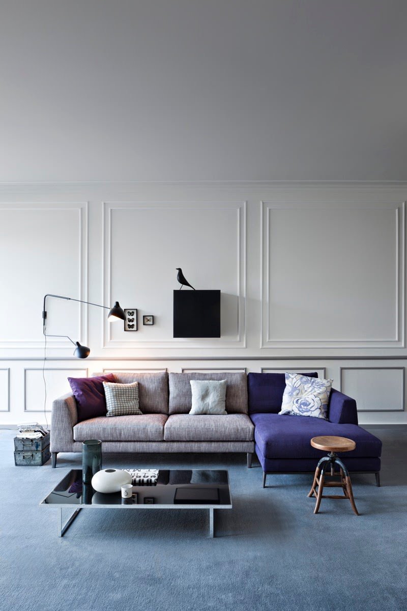 Ecco un esempio di soggiorno moderno scandinavo in cui i dettagli fanno la differenza. Un insolito accostamento di colori che parte dalla moquette blu fiordaliso, seguito da una parte del divano ad L in stoffa di colore blu indaco, finendo con i tocchi di nero del tavolino, del quadro e della lampada.