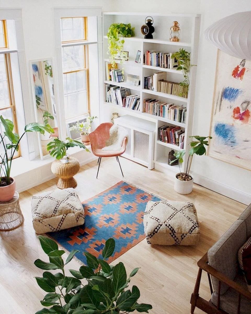 Immagine dall'alto di un soggiorno scandinavo pieno di colore e vitalità. Grandi finestre, pavimento in legno chiaro, tocchi di colore blu e rosso (tappeto, quadro e sedia) ed il verde delle piante.