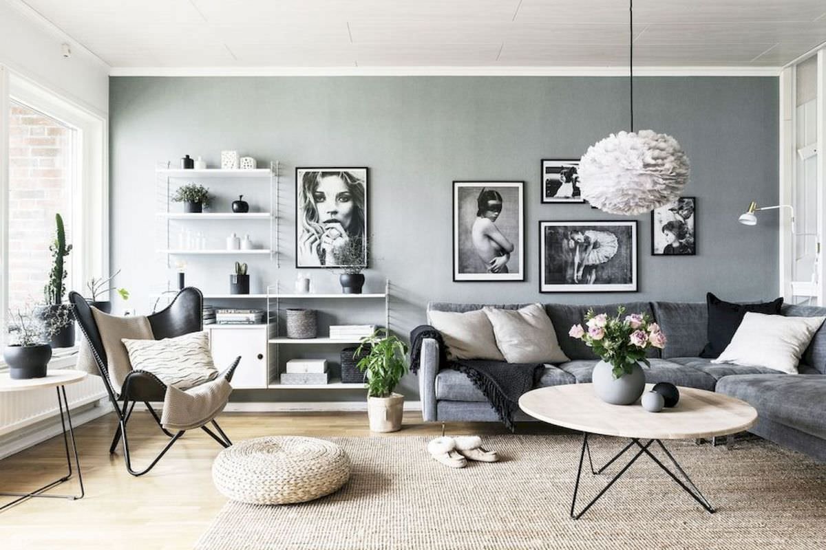 Immagine di un soggiorno scandinavo moderno in contrasti di bianco e nero (quadri, poltrona, cuscini, vasi) e tonalità di grigio (colore parete e divano) con accenti legno chiaro ed il verde naturale delle piante. Minimal, essenziale ma di grande impatto visivo.