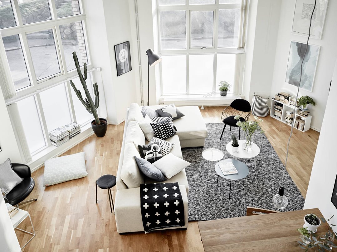 Vista dall'alto di un living scandinavo del design moderno ed elegante - arredi con contrasti in bianco e nero, pavimento in legno e grandi finestre - ispirazione arredamento casa moderna