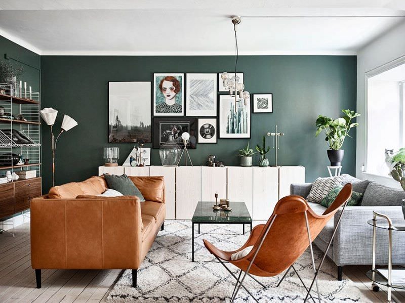 Una tinteggiatura decisa verde pino per le pareti di questo soggiorno scandinavo moderno. Il cuoio del sofà e della poltrona dona forza espressiva e carattere all'ambiente.