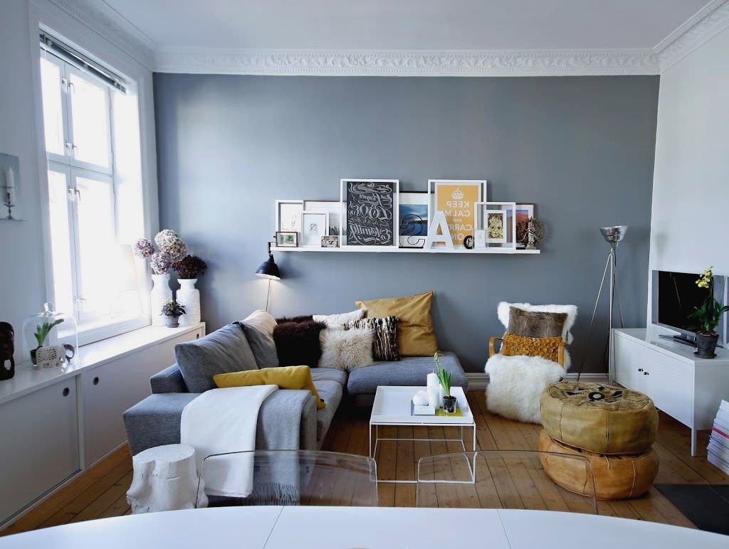 Piccolo soggiorno scandinavo contemporaneo con pareti e arredi in una combinazione di colori bianco e grigio abbinati a toni naturali: marrone chiaro e giallo ocra.