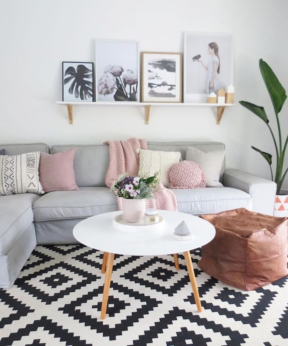 Immagine soggiorno scandinavo femminile, stile contemporaneo, in colori morbidi (grigio e rosa pastello) in contrasto con il colore deciso (contrasto di bianco e nero) del tappeto. Abbinamento di delicatezza e dinamicità.