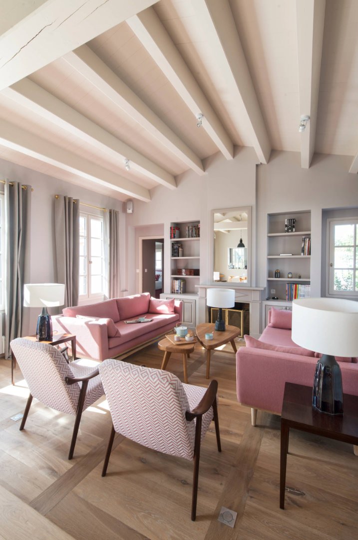 Scala di rosa per questo salotto scandinavo che denota un tocco femminile. La posa del parquet riprende il disegno delle travi in vista del tetto, dando ritmo allo spazio.