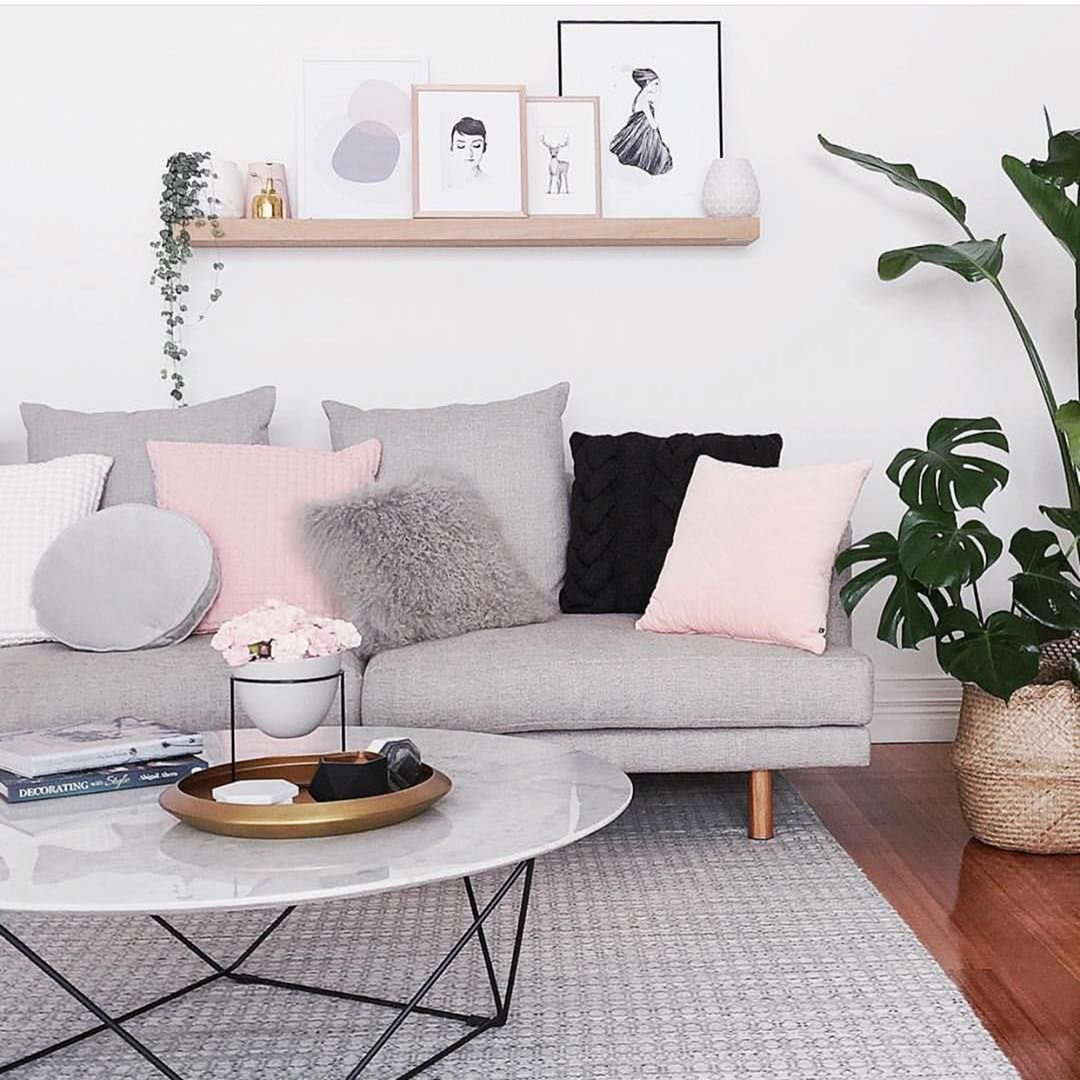 Immagine angolo relax con accostamento di colori e pattern in perfetto stile nordico moderno - stile femminile con alcuni cuscini rosa e legno di tonalità chiara, divano e tappetto grigio