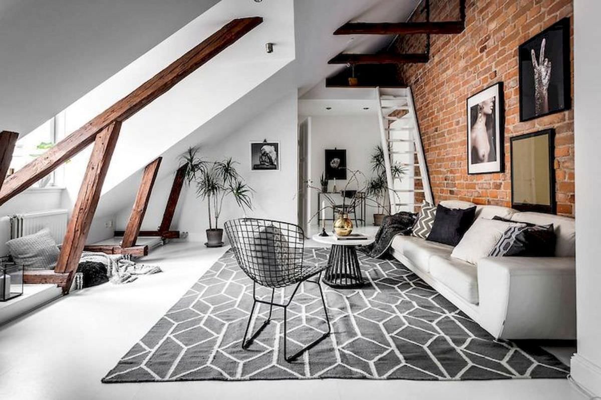 Lo stile scandinavo si abbina allo stile industrial in questa mansarda. Dominano l'atmosfera la parete in mattoni a vista, le travi in legno e le grandi finestre che illuminano l'ambiente.