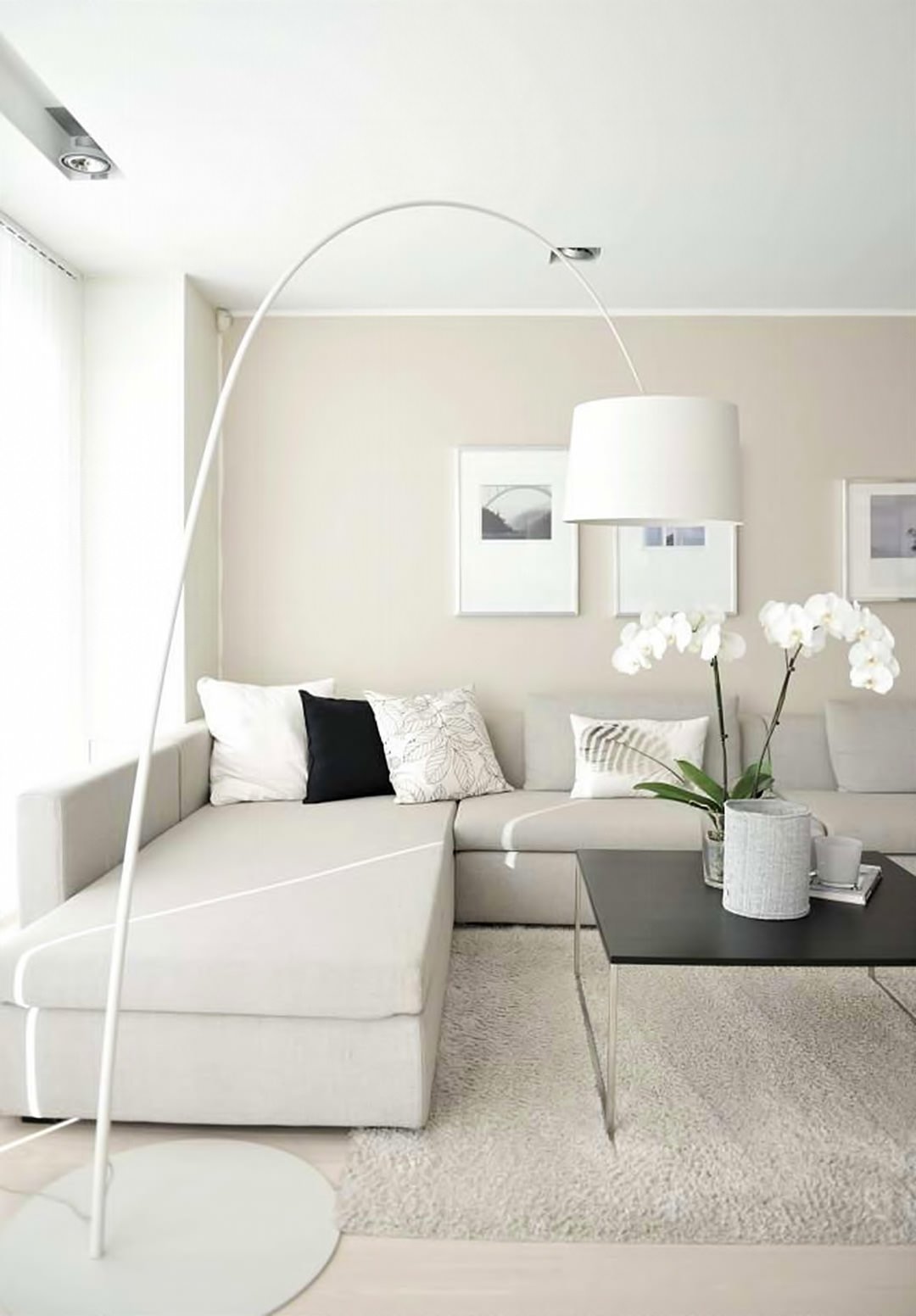 Immagine soggiorno scandinavo moderno ed elegante, in toni di grigio e beige con alcuni contrasti di nero. Pavimento in legno chiaro, perfettamente abbinato al colore delle pareti - divano ad L in tessuto, lampada ad arco